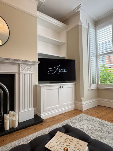 Elegant living room with white cabinetry, fireplace, and a book on a plush ottoman.