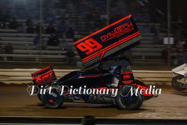 Sprint car racing on a dirt track at night.
