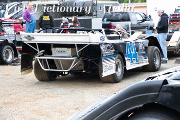 Race car number 44 parked with people around in a dirt area.