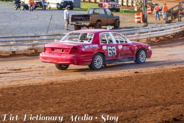 Red race car on dirt track during race.