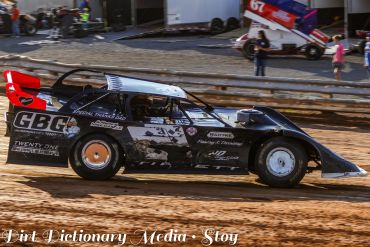Black dirt track race car racing on a dirt track.