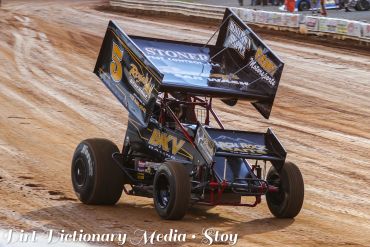 Black sprint car racing on dirt track.