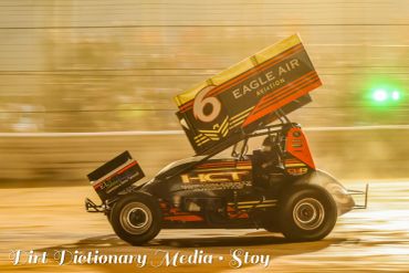 A sprint car racing on a dirt track with motion blur.