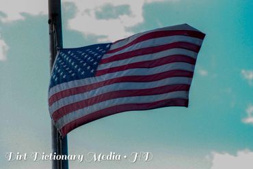 An American flag waving against a cloudy sky.