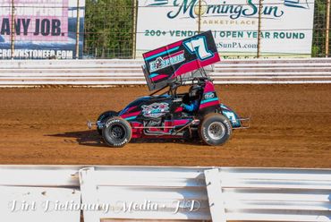 A colorful sprint car with the number 7 races on a dirt track.