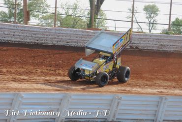 A sprint car racing on a dirt track during a race.