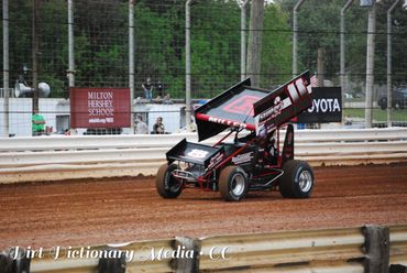 A sprint car racing on a dirt track during a race.