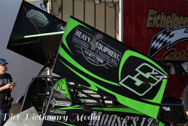 Green and black sprint car with the number 3 on its wing at a racing event.