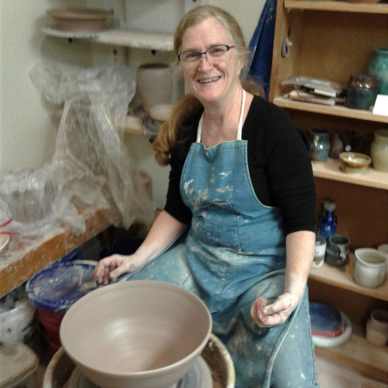 woman throwing large bowl on pottery wheel