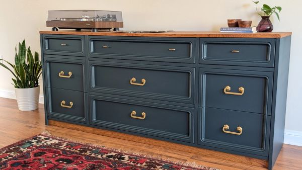 Stylish dark blue dresser with brass handles and wooden top, decorated with a turntable and plant.