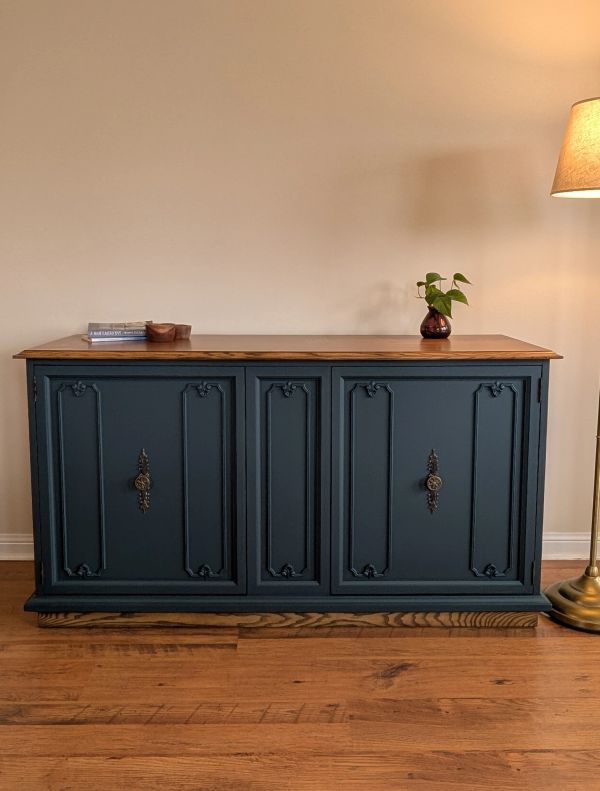 Elegant dark blue cabinet with wooden top, decorated with a small plant and books.