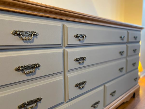 Close-up view of a vintage dresser with ornate handles and a wooden top.