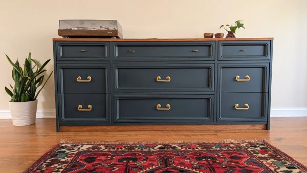 Elegant blue dresser with gold handles and wooden top.