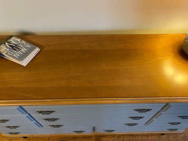 Wooden dresser with blue drawers and a book on top.