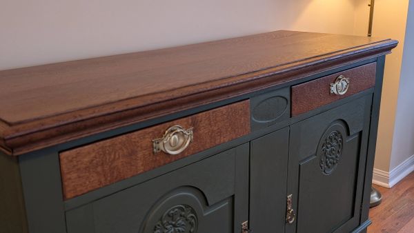 Vintage wooden cabinet with decorative handles and intricate carvings.