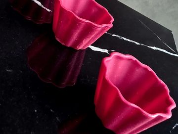 Pink silicone molds on a black marble surface.