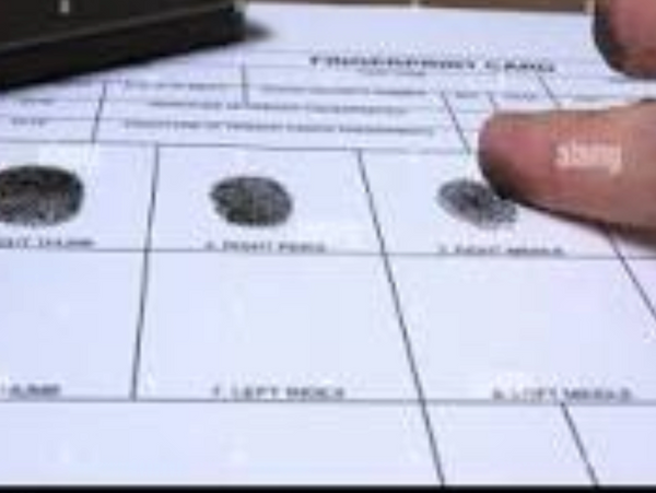 Close-up of a fingerprint card with visible fingerprints and a person's finger.