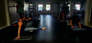 People exercising together in a dimly lit gym studio.
