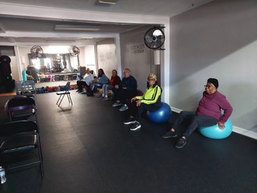 A group of people sitting on exercise balls in a gym room.