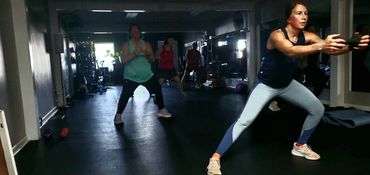 People doing group exercise in a gym with focused expressions.
