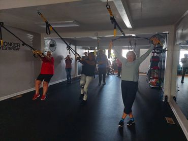 People exercising with suspension trainers in a gym.