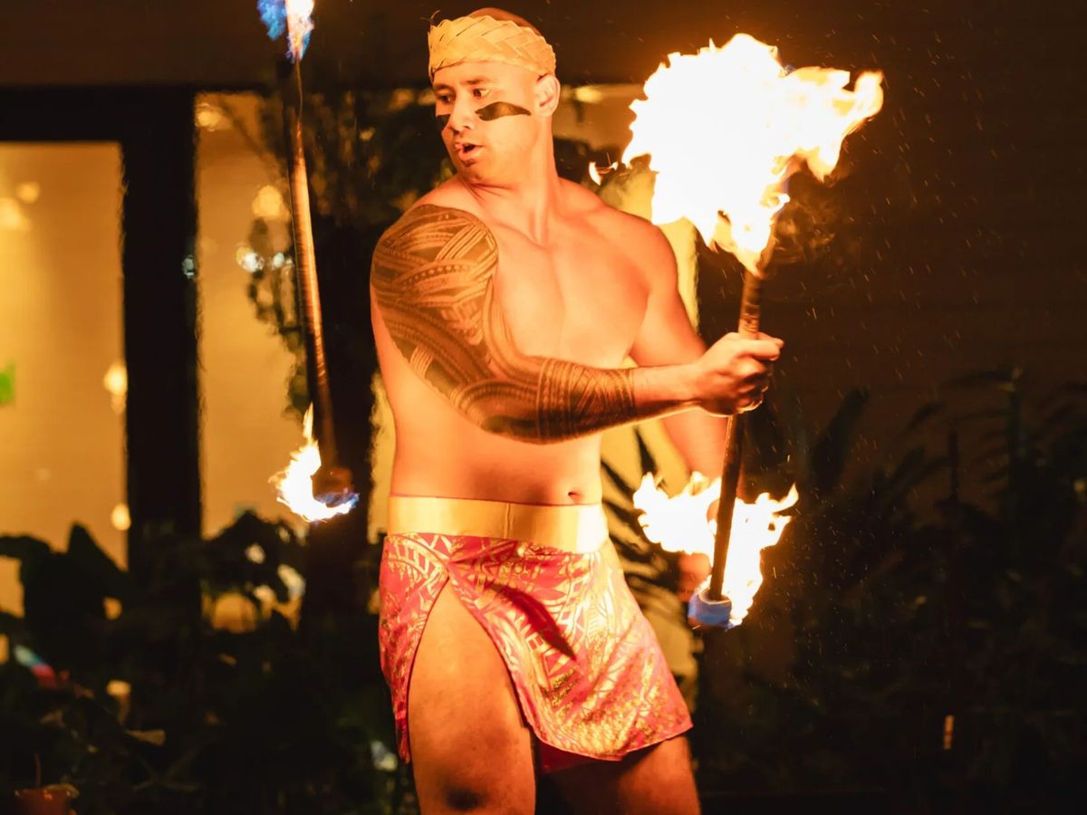 Fire knife dancer holding a flaming knife at Queens Waikiki Luau