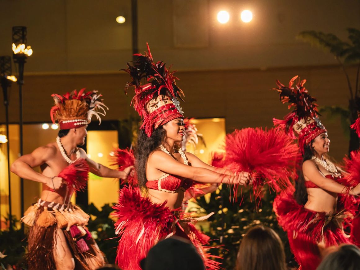 Queens Waikiki Luau performers in red costumes on stage.