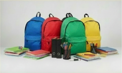 Four colorful backpacks with school supplies arranged in front.