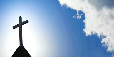 Silhouette of a cross against the bright sky.