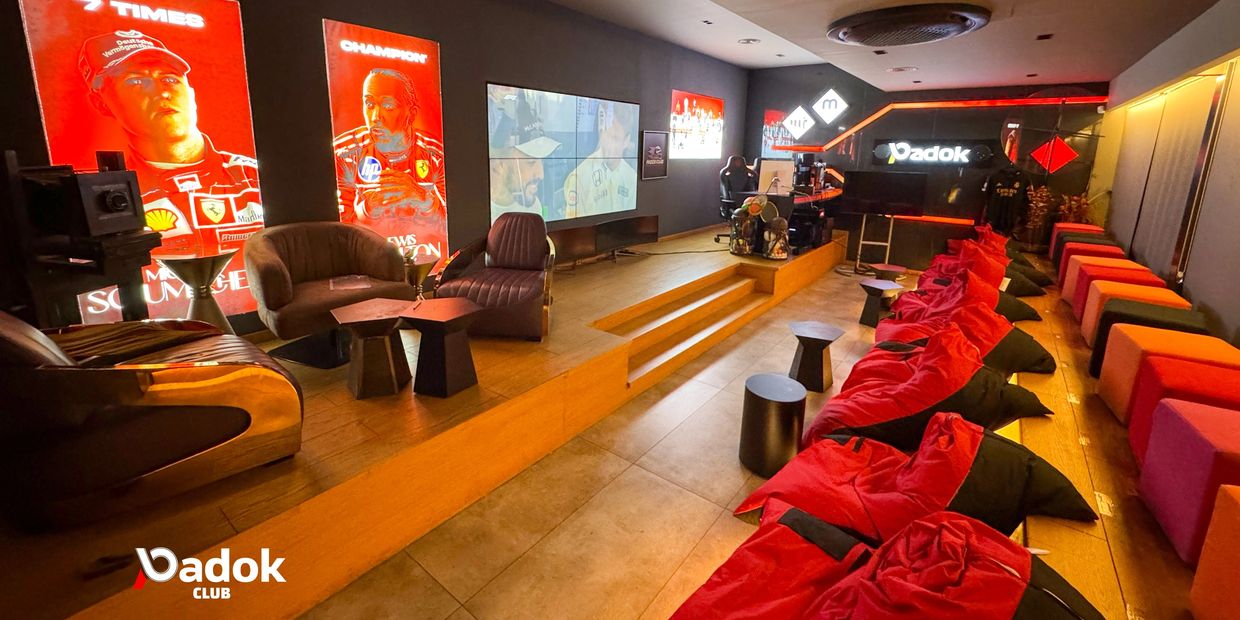 A modern club lounge with bean bags, armchairs, and bright racing-themed posters.