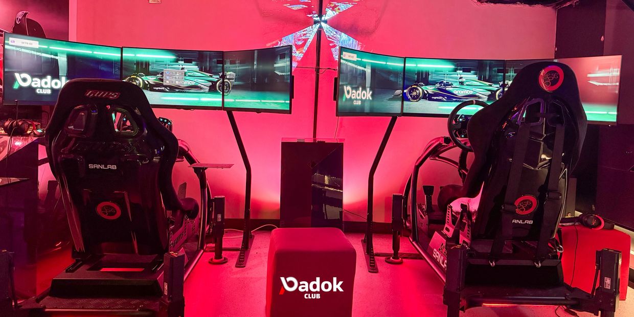 Two racing simulator setups with triple monitors in a red-lit gaming room.