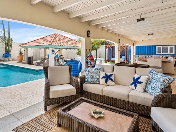 Covered outdoor lounge at Paradise in Aruba vacation home with patio seating near the pool