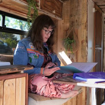 Woman reading a document inside a cozy wooden camper van.
