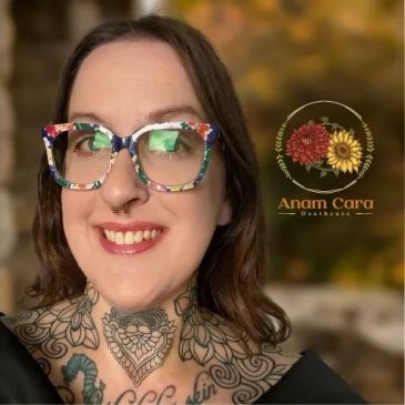 Smiling woman with floral glasses and intricate neck tattoos.