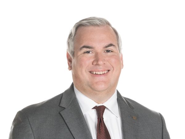Professional man in gray suit smiling at the camera.