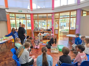 Children and adults seated in a circle in a classroom.