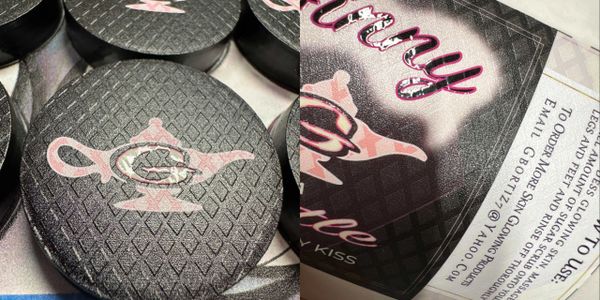 Black puck with a pink genie lamp logo on a diamond pattern surface.