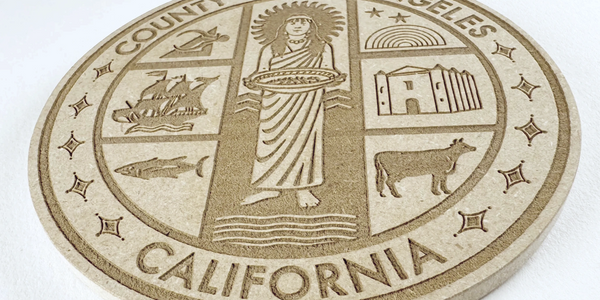 Engraved wooden seal of Los Angeles County, California with symbolic images.