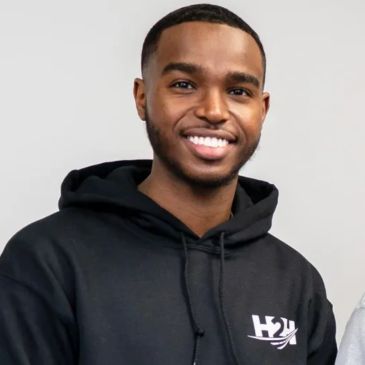 Smiling young man in a black hoodie.