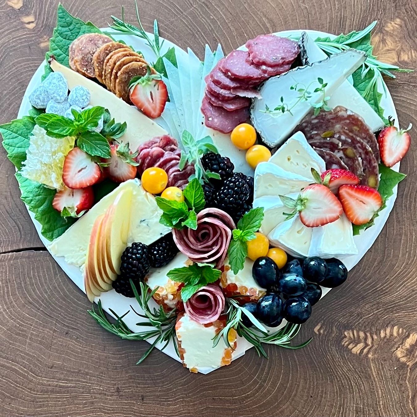 a heart shaped platter of cheese and fruit