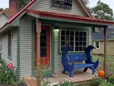Small green house with a blue crab-shaped bench.