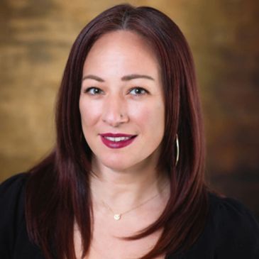 Portrait of a woman with long red hair, smiling.
