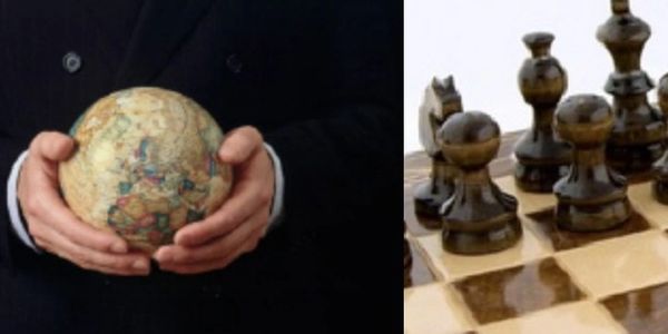 Person holding a globe beside a chessboard with black chess pieces.
