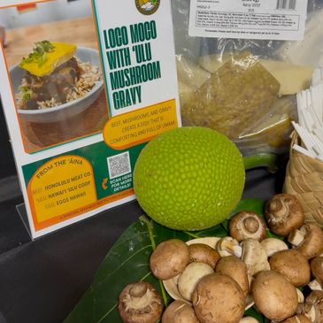 Fresh mushrooms and local fruit displayed alongside Loco Moco with 'Ulu Mushroom Gravy' sign.