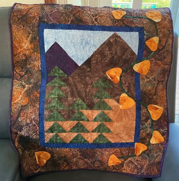 Handmade quilt with mountain and tree design.