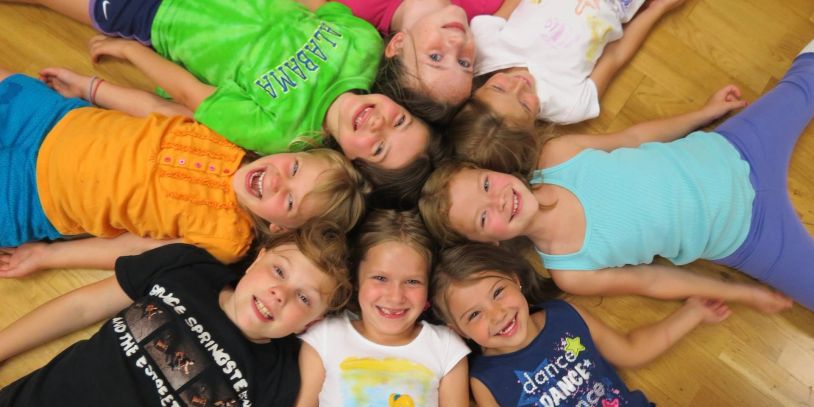 Group of smiling children lying in a circle.