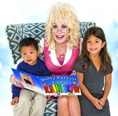 Dolly Parton reads a colorful book to two children on her lap.