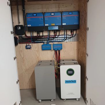 Electrical control panel with JouleTech branded devices mounted on a wooden board.