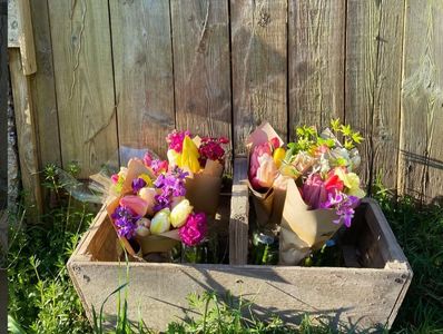 Colorful flower bouquets in a rustic wooden crate against a wooden fence.