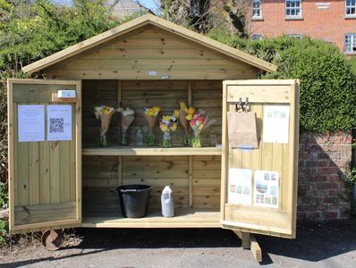 A wooden flower stand with bouquets and informational papers on the doors.